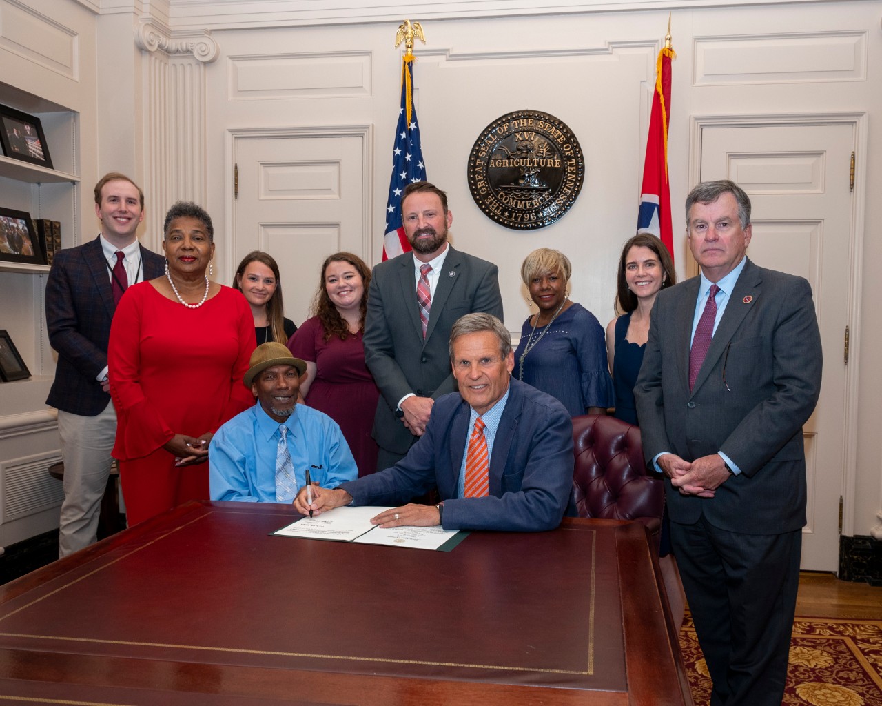 Martez Williams, Council member, at bill signing of "Precious Cargo Act", summer 2021 with Gov. Bill Lee and other advocates for the bill group of about a dozen people seated and standing by the Governor at the capitol while he signs the legislation, posing for a group photo
