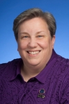 headshot of Alicia Cone, a white woman with short gray hair and an embroidered purple blouse with a state of TN and a leadership academy pin on it