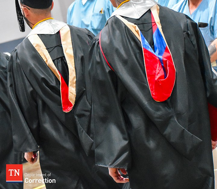 Photo of the back of two graduates in black gowns.