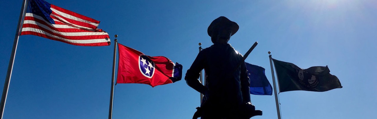 Minuteman statue with American Flag and Tennessee Flag in background 