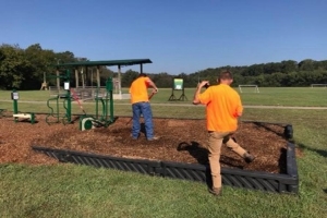 Two men with tools installing outdoor athletic equipment